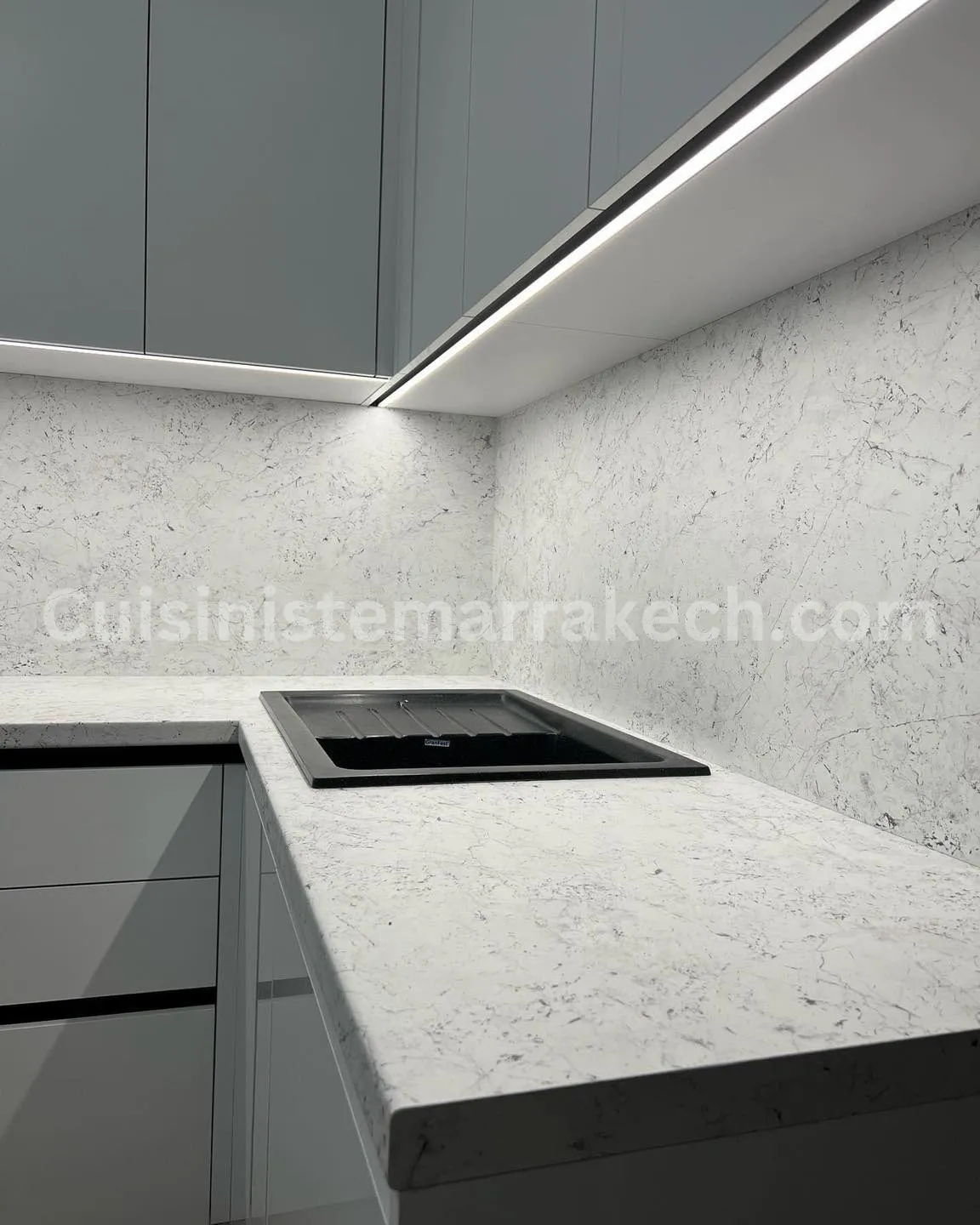 Détail d'un plan de travail et d'une crédence en quartz blanc marbré avec réglette LED
